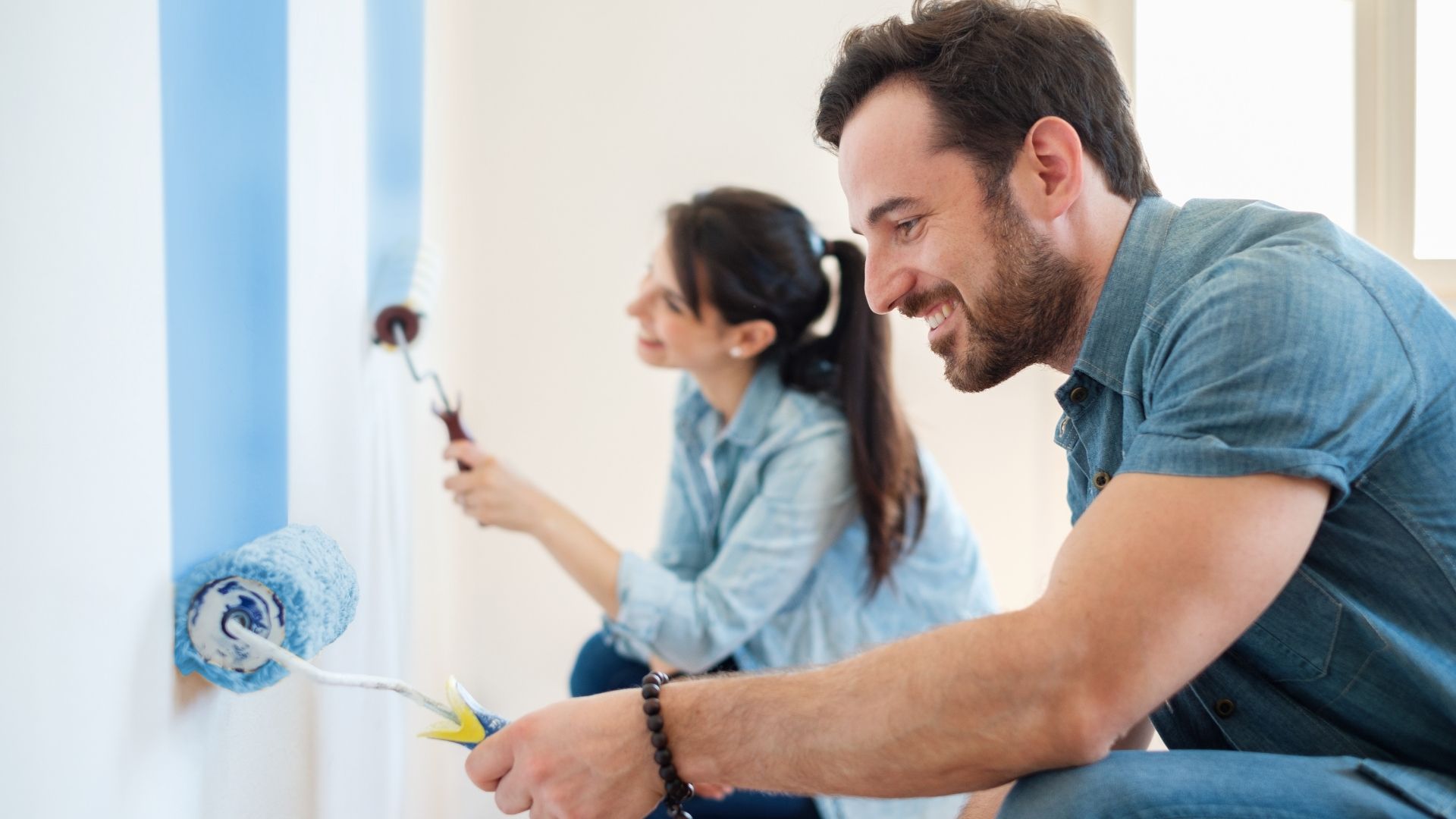 Man and woman painting wall together indoors