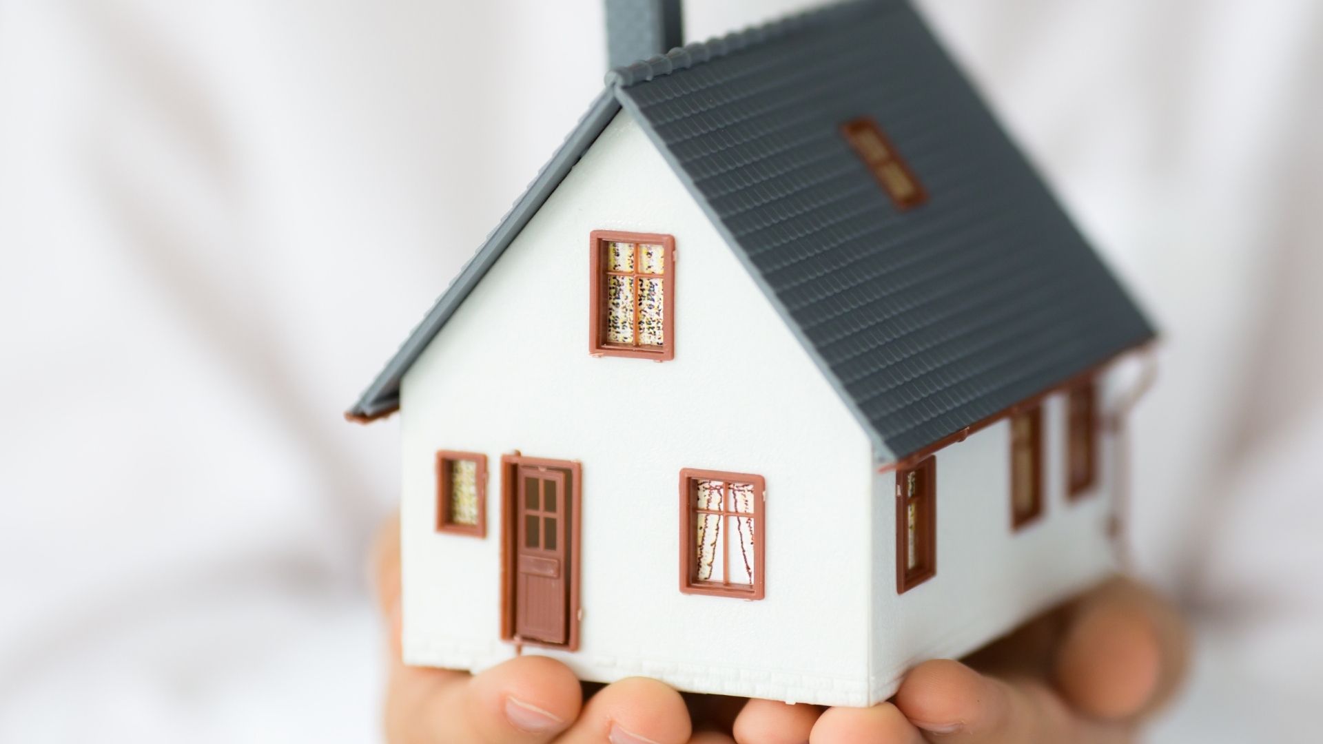 Hands holding a small model of a house