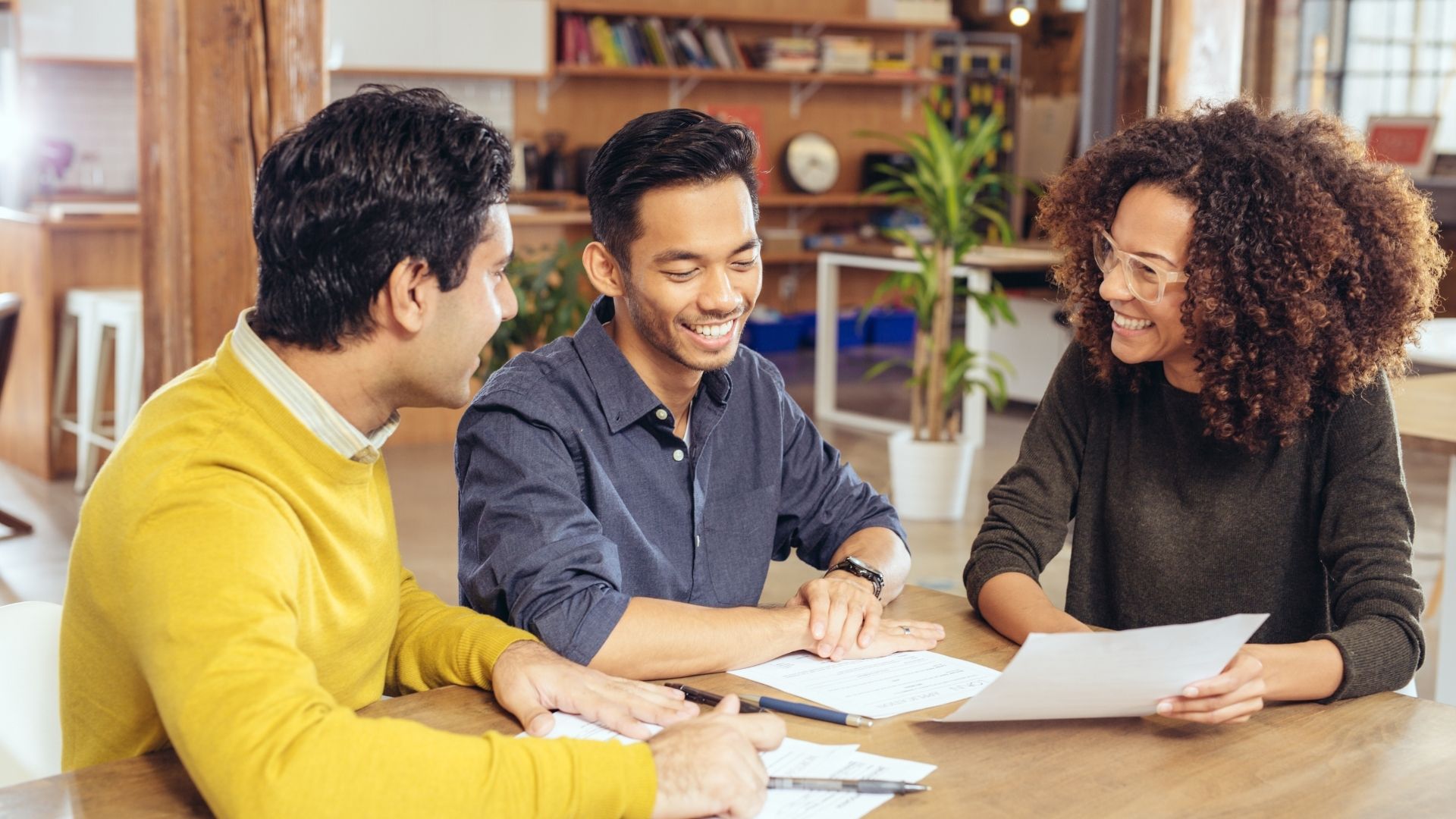 Three colleagues discussing documents in office