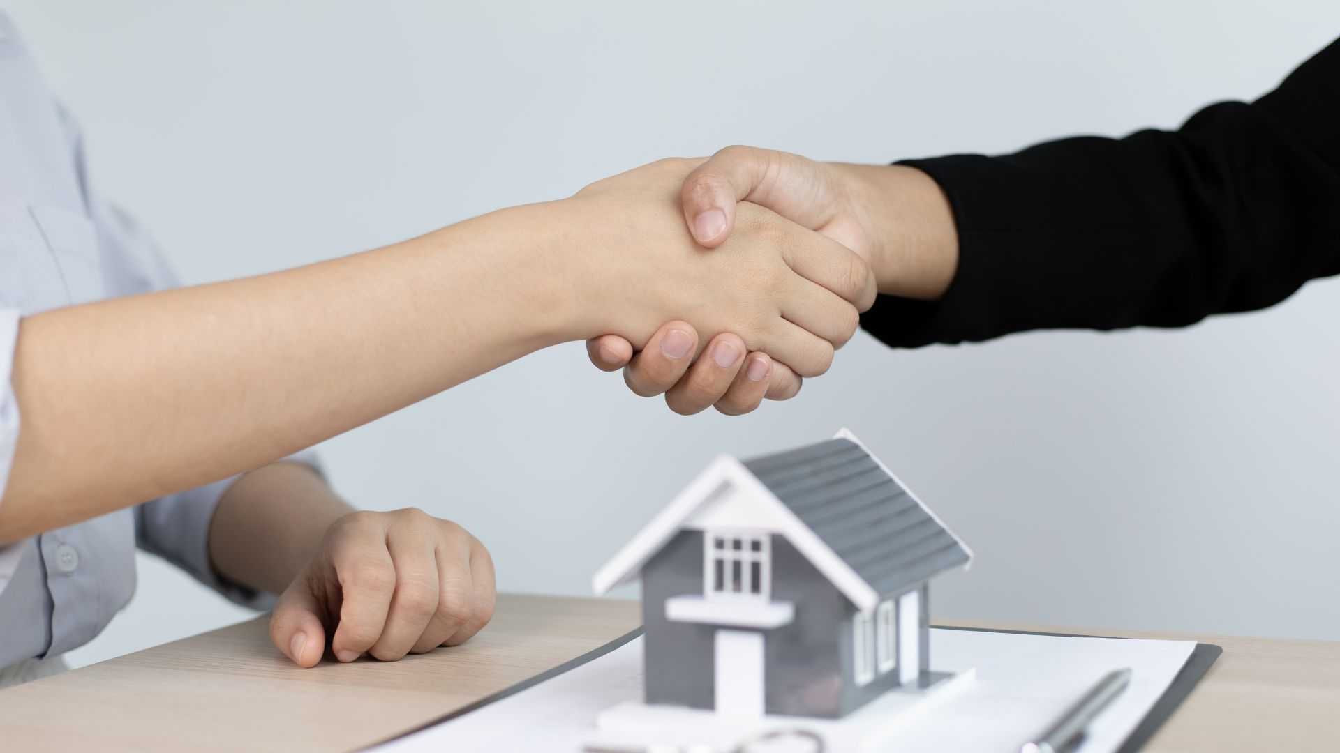 Handshake over house model, real estate agreement