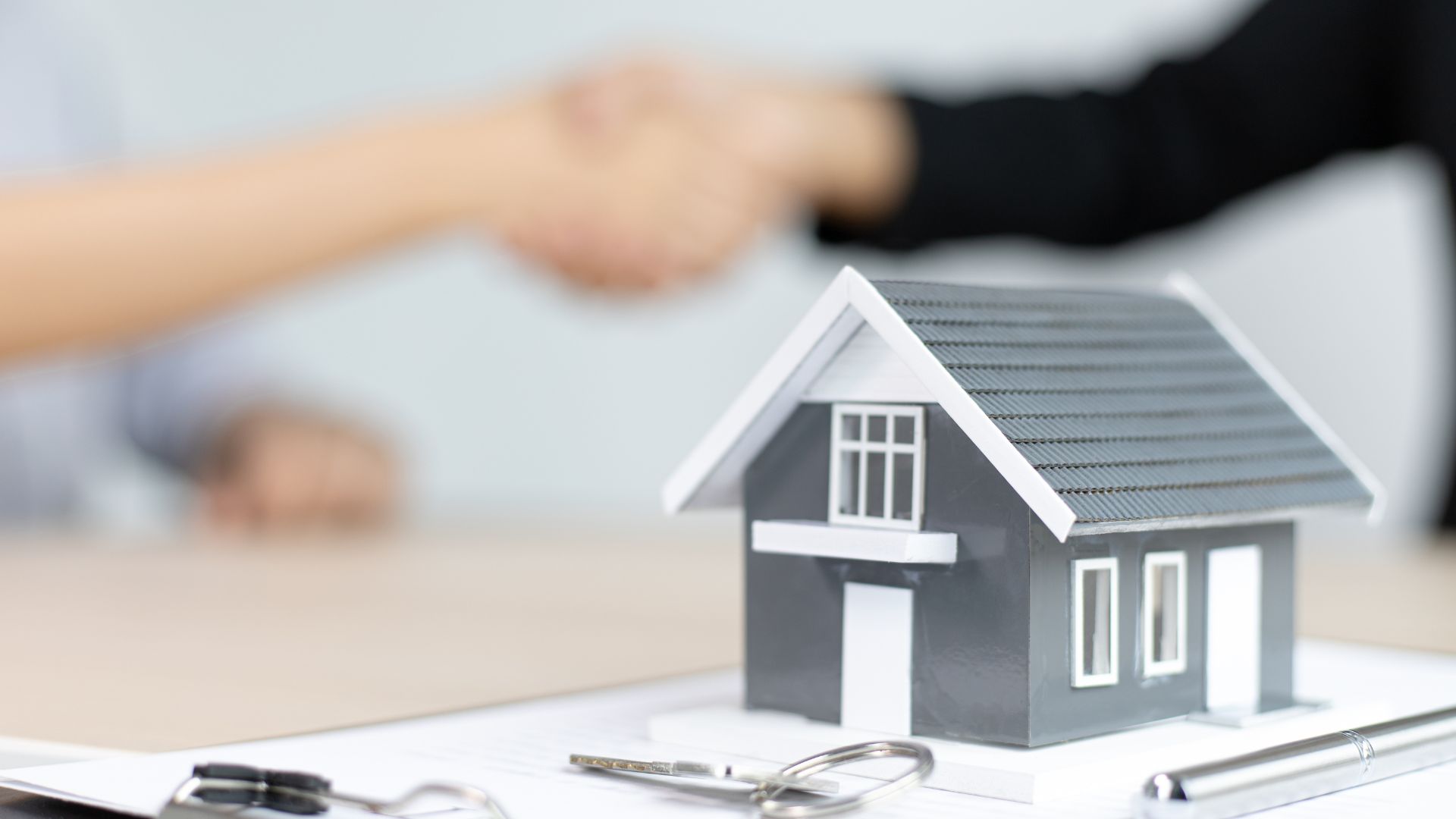 Handshake over house model, real estate agreement