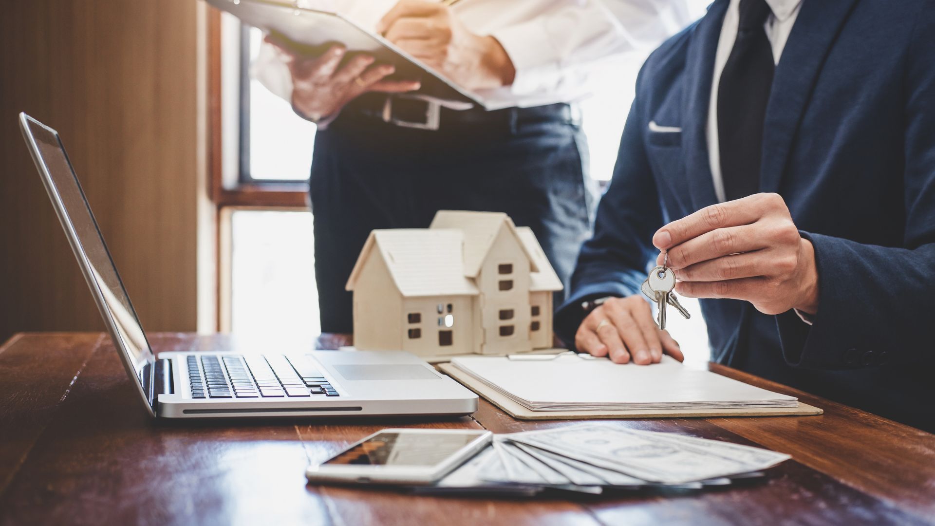 Real estate agent handing keys over house model