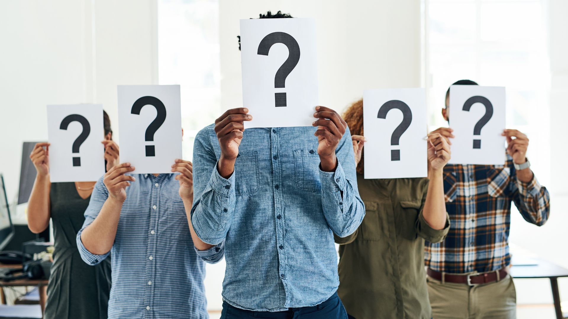 Group holding question mark signs, faces obscured