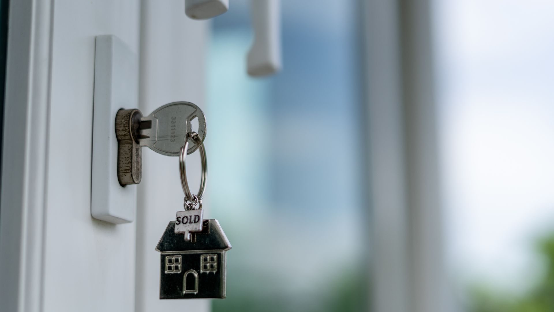 House key in lock with sold keychain on door