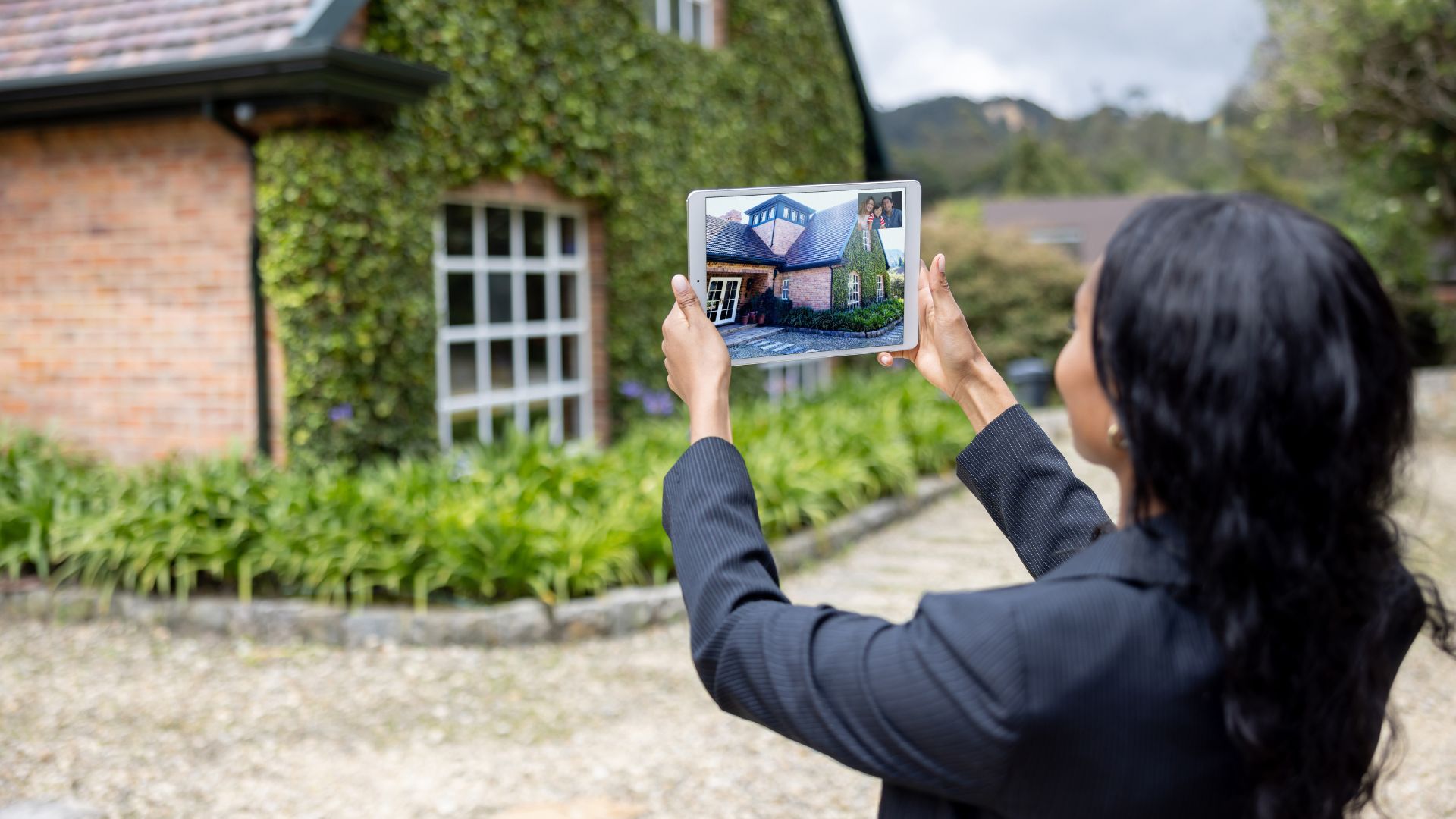 Woman comparing house photo on tablet outdoors