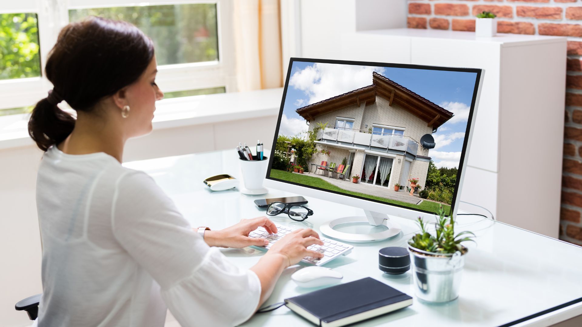 Woman using computer with house image on screen