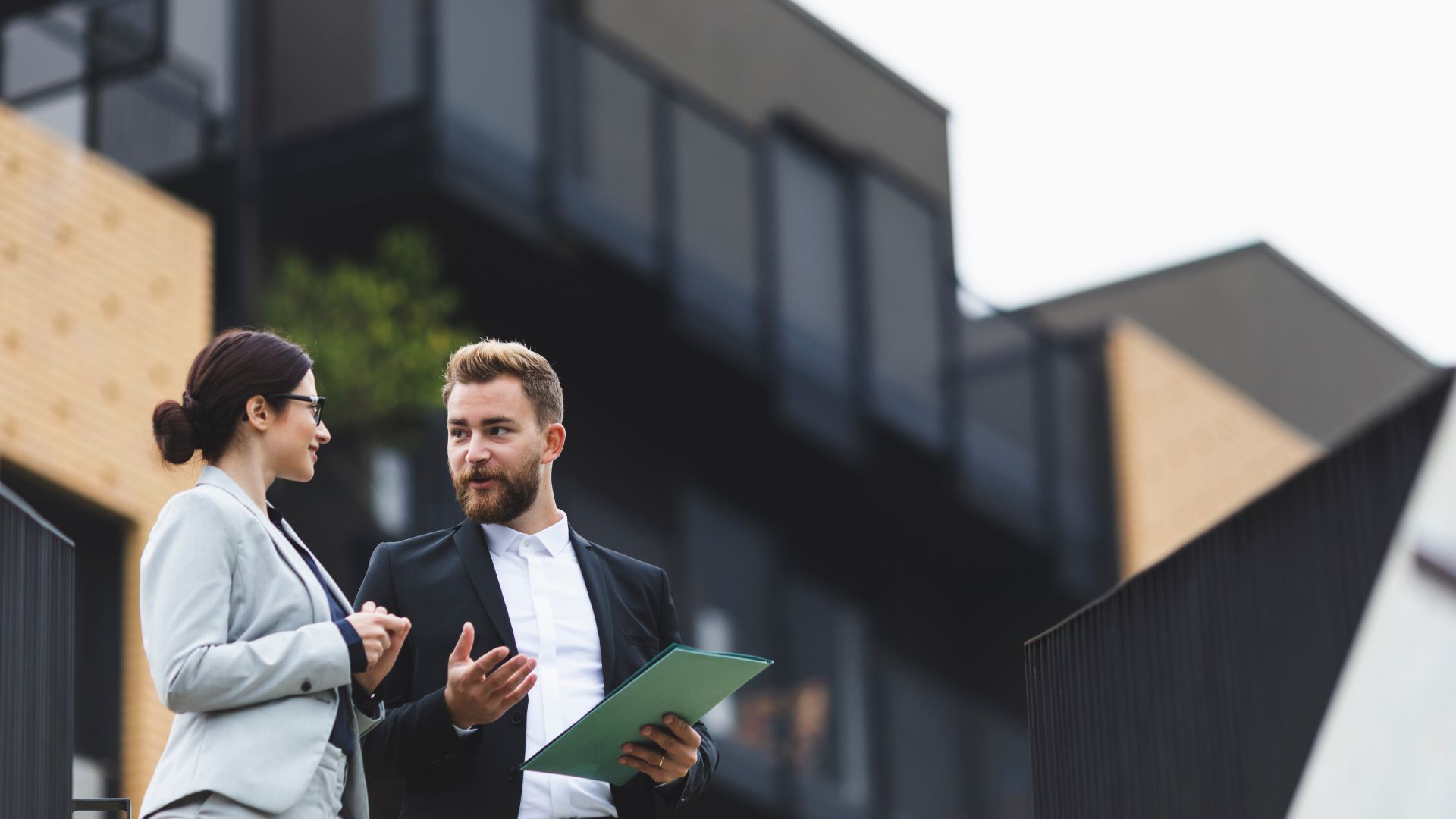 Business professionals discussing outdoors near modern buildings
